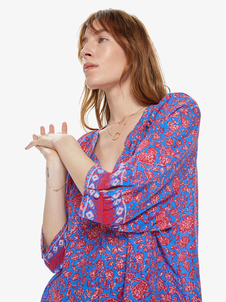 Front close up view of a woman wearing a flowy button down top featuring 3/4 length sleeves and a blue and pink floral print.