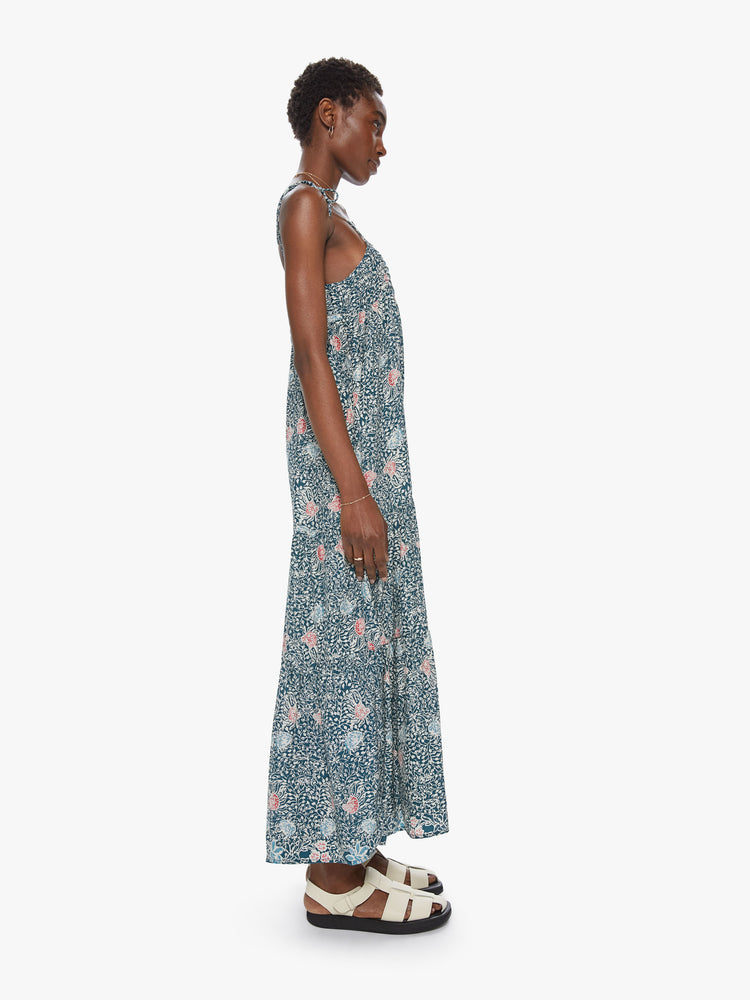 Side view of a spaghetti strap dress featuring a long, flowy fit and a green floral print.