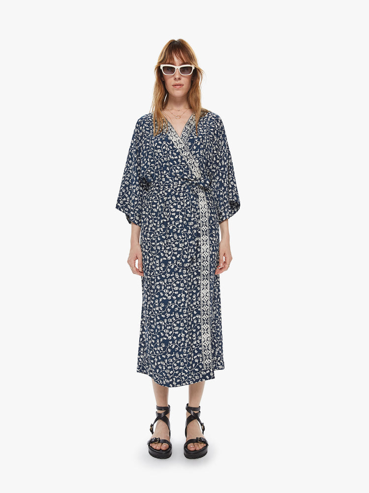 Front view of a loose fit wrap dress featuring wide 3/4 length sleeves and an indigo floral print.