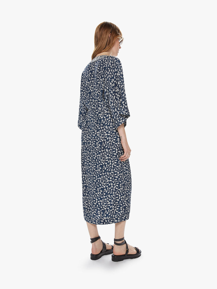 Back view of a loose fit wrap dress featuring wide 3/4 length sleeves and an indigo floral print.