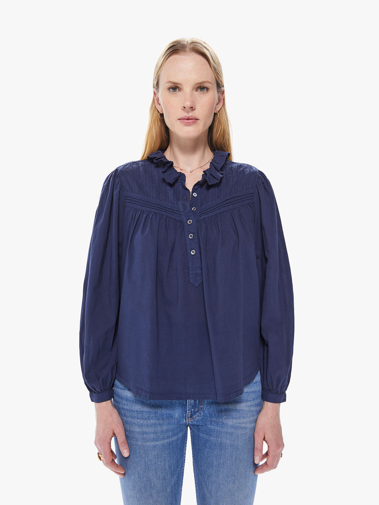 Front view of a women's navy blue long sleeve blouse with a button-front placket and ruffle neckline