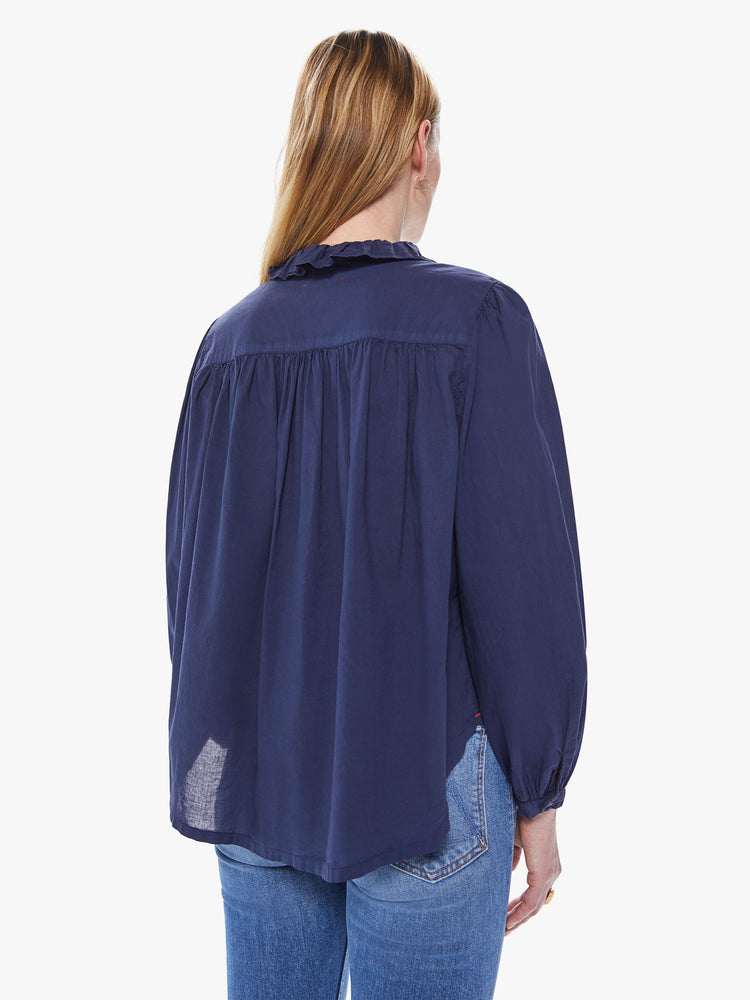Back view of a women's navy blue long sleeve blouse with a button-front placket and ruffle neckline