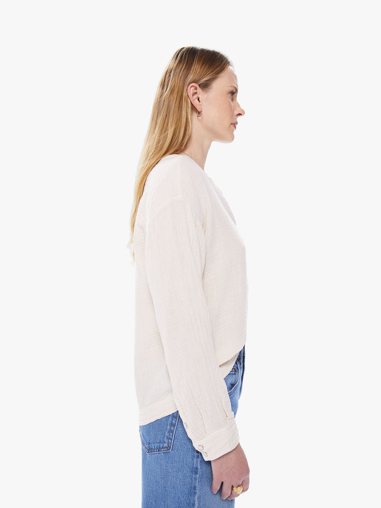 Side view of a women's ivory colored long sleeve shirt with a snap button front placket and patch pocket