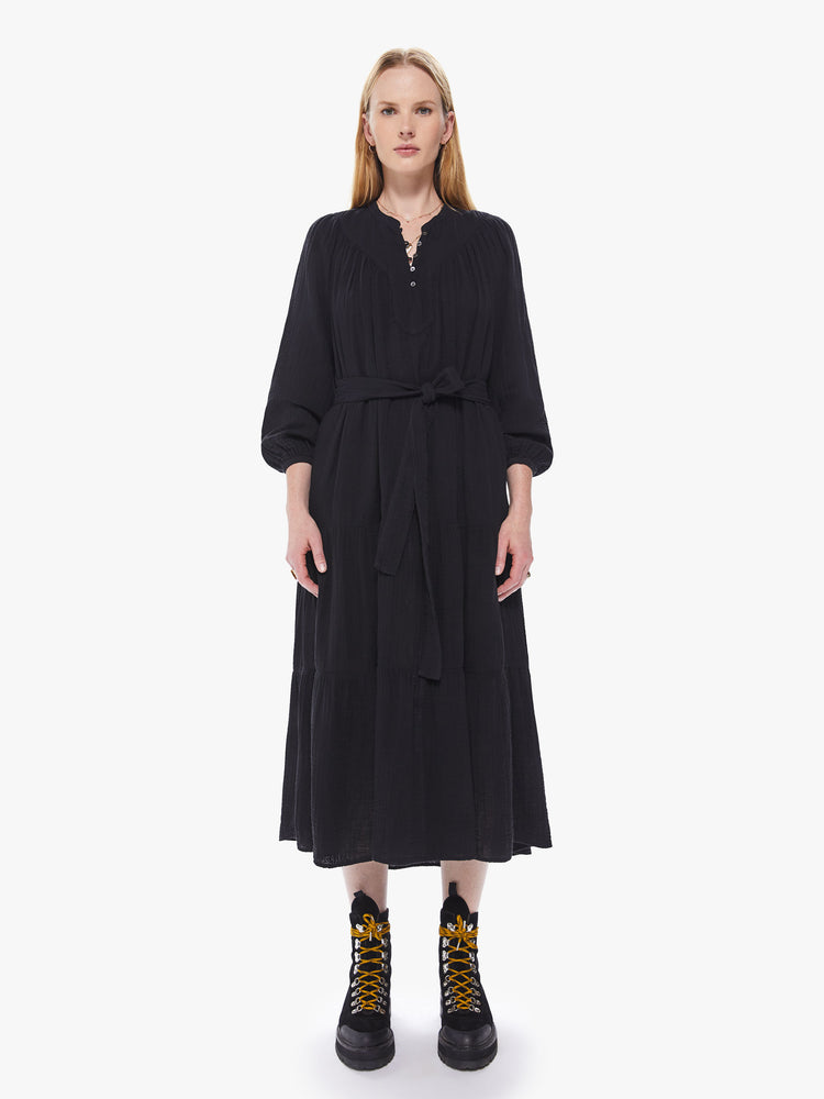 Front view of a women's black midi dress with long sleeves, a belted waist, and a button-front collar