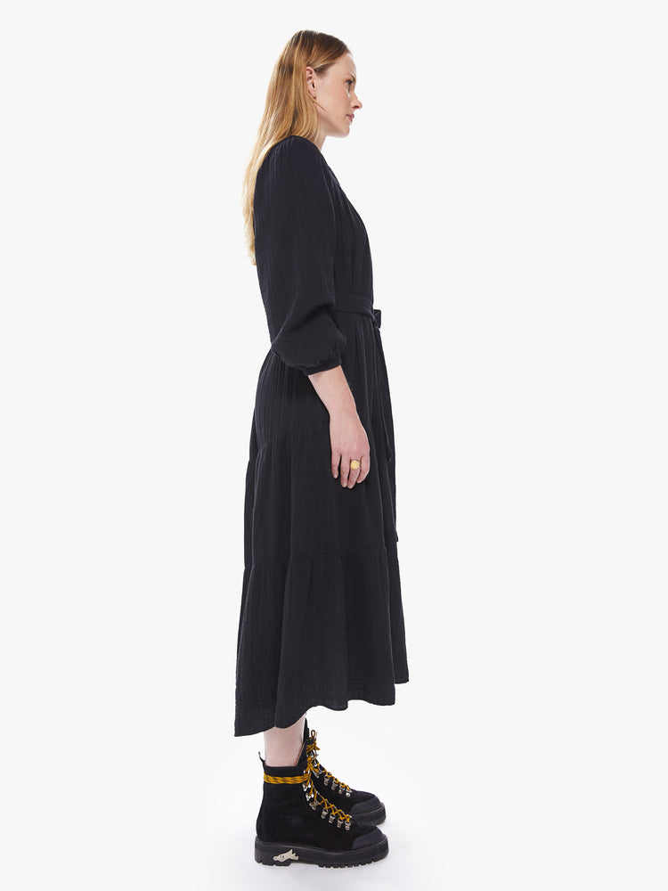 Side view of a women's black midi dress with long sleeves, a belted waist, and a button-front collar