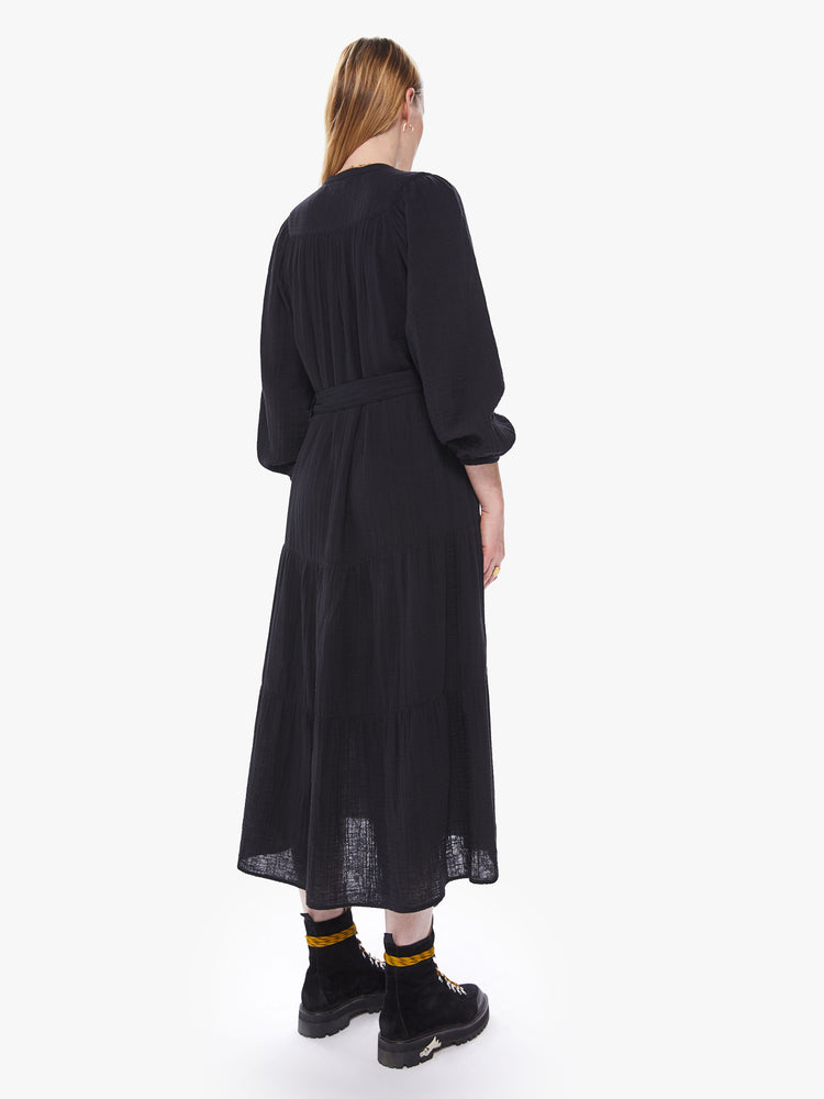 Back view of a women's black midi dress with long sleeves, a belted waist, and a button-front collar