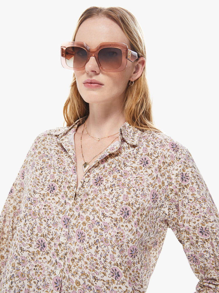 Front detail view of a women's cream colored button down shirt with an all-over yellow and pink floral print