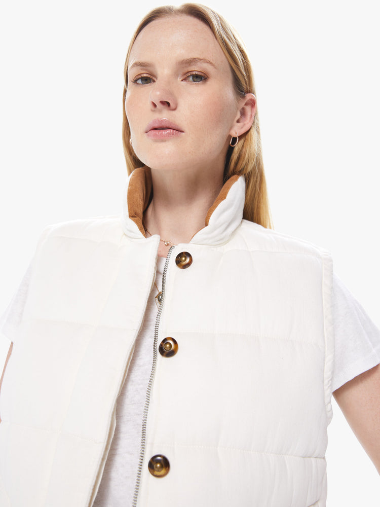 Front detail view of a women's ivory reversible vest with beige floral lining and tortoise buttons