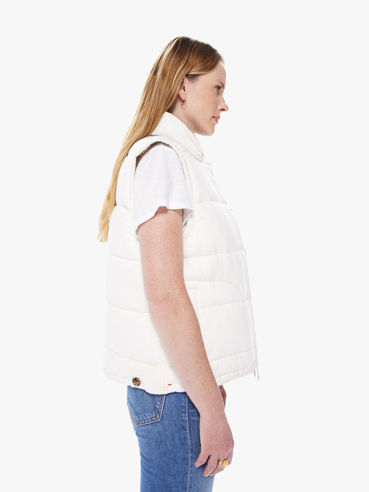 Side view of a women's ivory reversible vest with beige floral lining and tortoise buttons