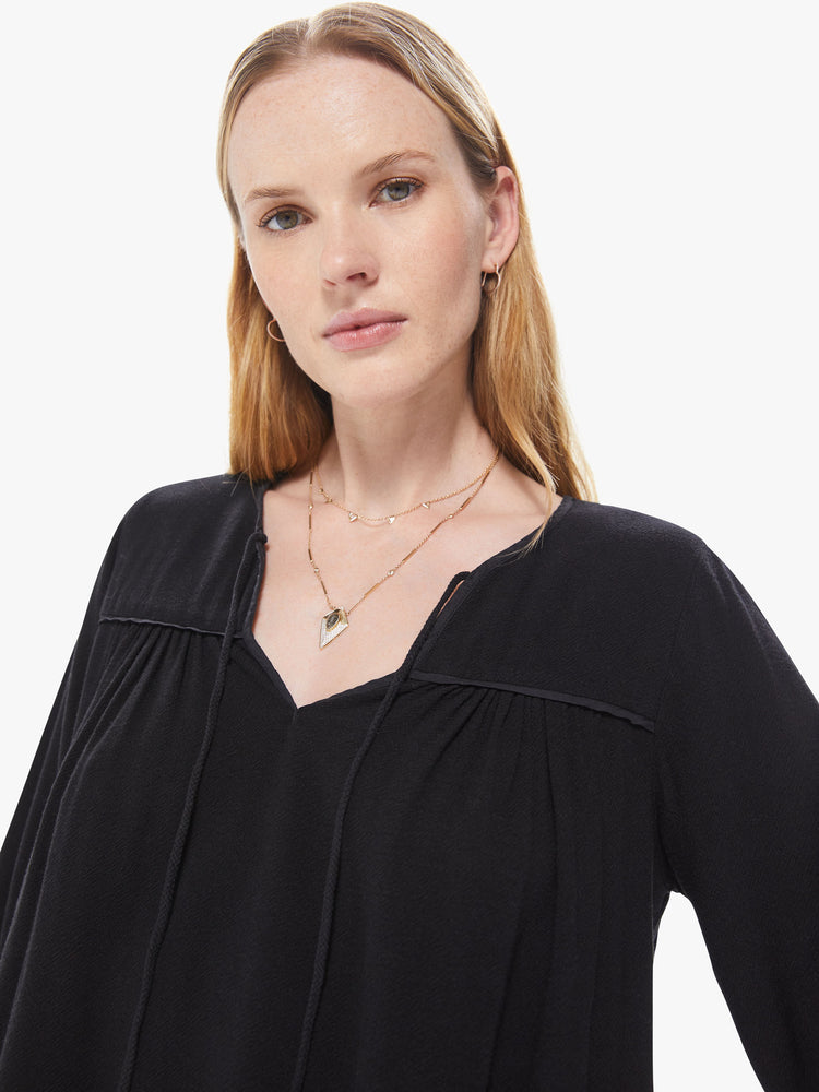 Front close up view of a women's black long sleeve blouse, featuring a flowy fit and a keyhole neck with tie.