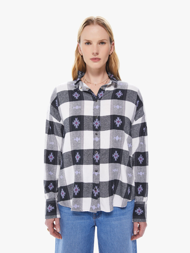 Front view of a women's long sleeve button down featuring a ruffled collar, a black and white gingham print with purple details, and a loose oversized fit.