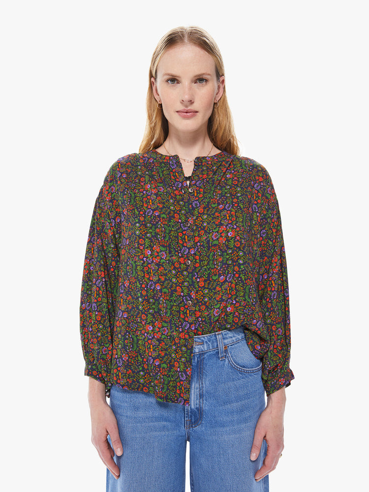 Front view of a women's button down blouse featuring a colorful floral print,a crew neck collar, billow sleeves, and a loose fit.