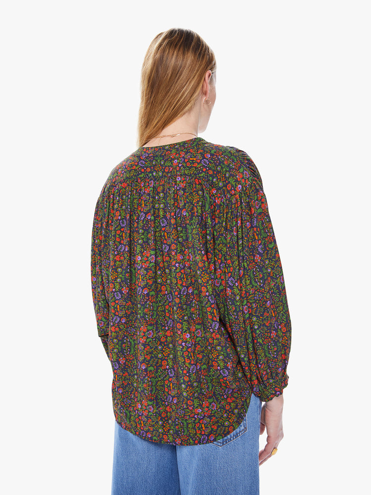 Back view of a women's button down blouse featuring a colorful floral print, a crew neck collar, billow sleeves, and a loose fit.