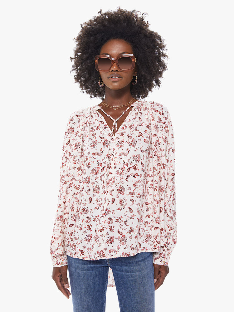 Front view of a womans long sleeve blouse, featuring an off white with red floral print, billowed sleeves, and a v neck with tie.
