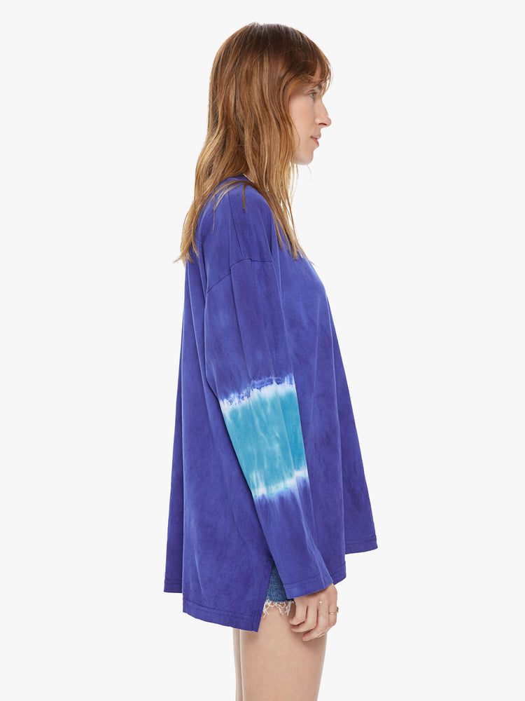 WOMEN Side view of a woman wearing a blue long sleeve crew featuring an oversized fit and tie dye details on the arms.