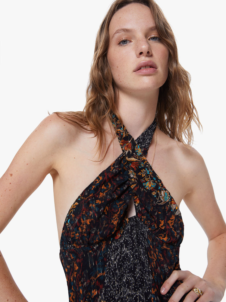 Front close up view of a womens dark printed dress featuring a a halter neck and an empire waist.