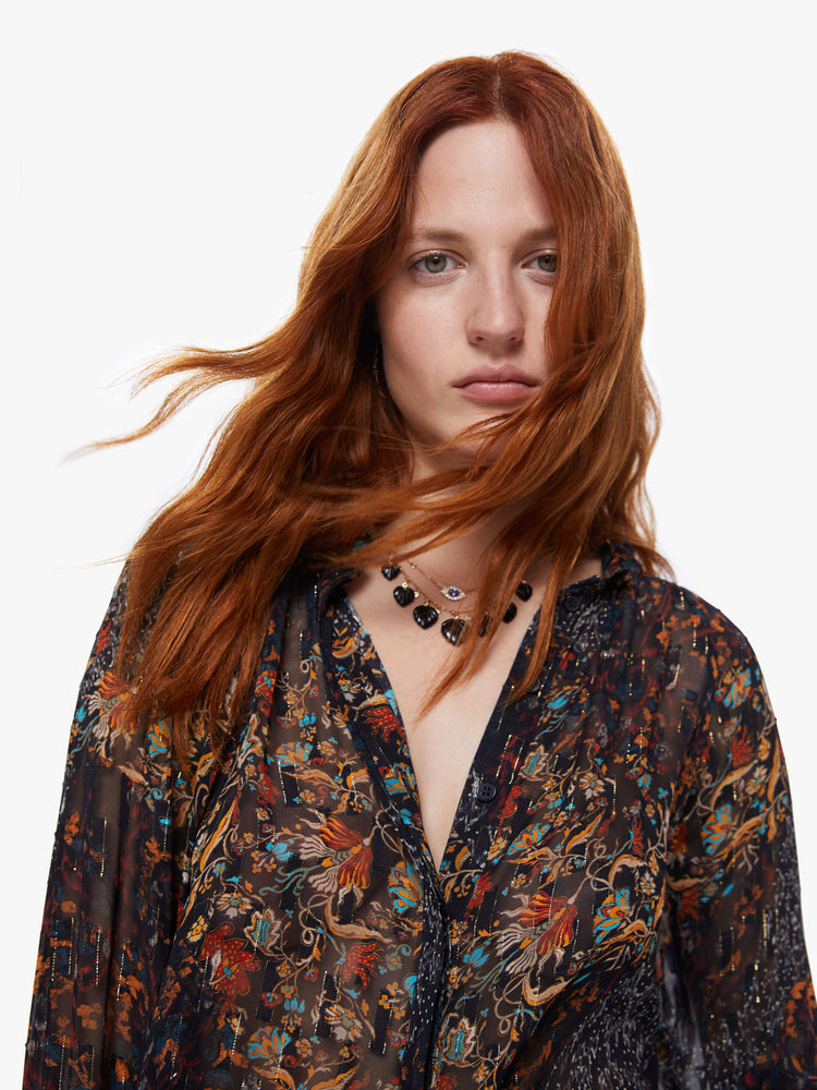 Front close up view of a womens dark printed button down blouse featuring loose long sleeves with smocked cuffs and a flowy fit.