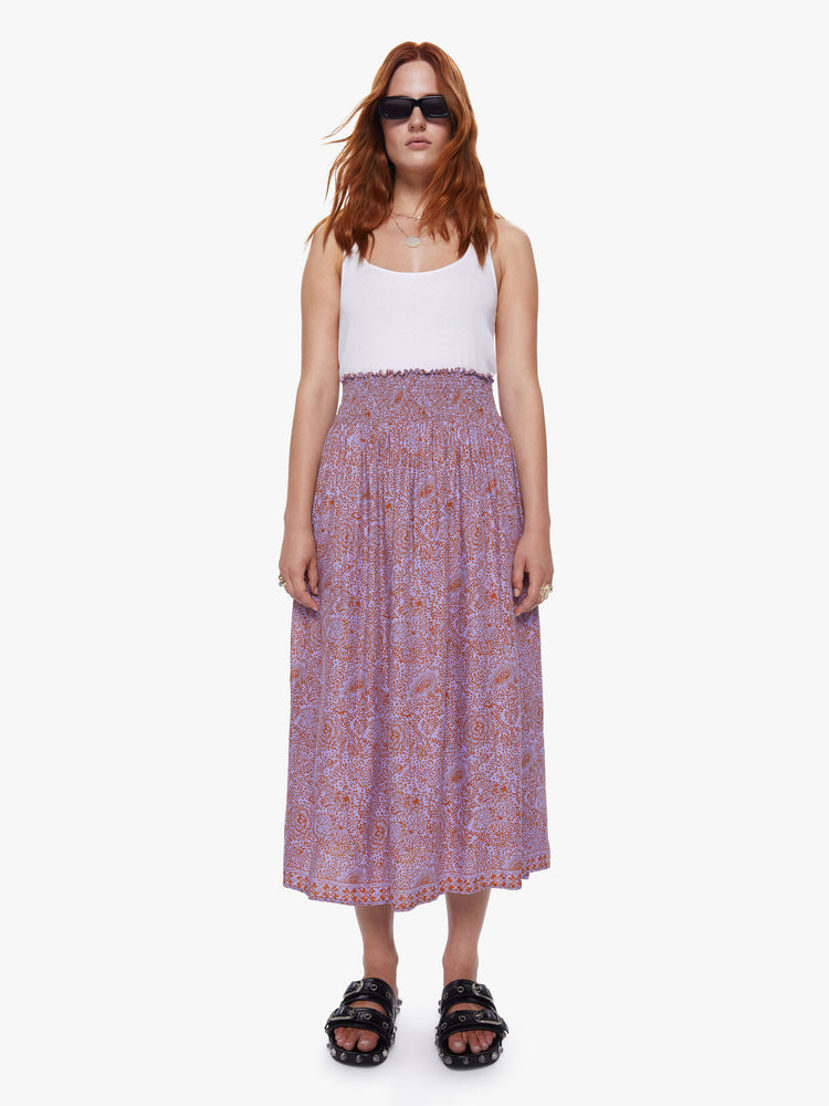 A front view of a woman wearing orchid-purple and rust floral print maxi skirt.