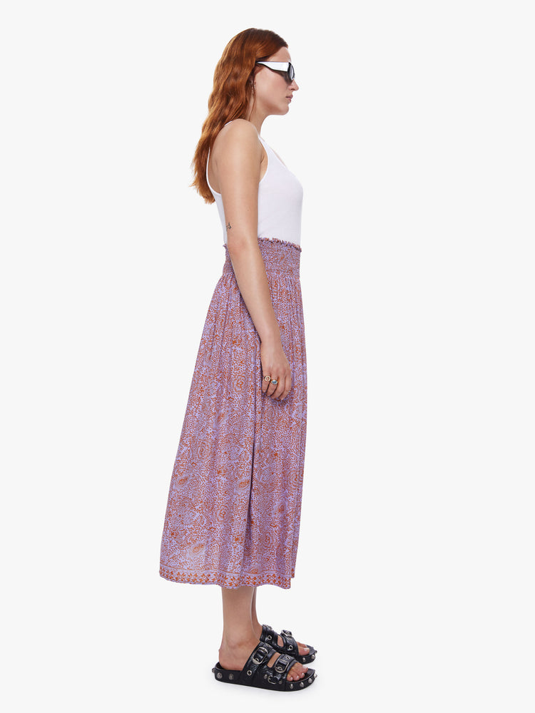 A side view of a woman wearing orchid-purple and rust floral print maxi skirt.