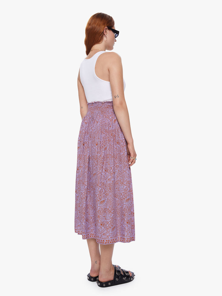 A back view of a woman wearing orchid-purple and rust floral print maxi skirt.