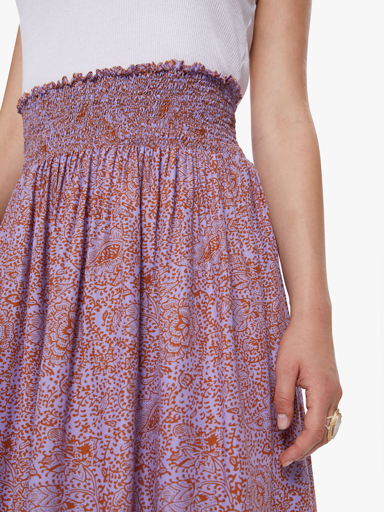 A detail view of a woman wearing orchid-purple and rust floral print maxi skirt.