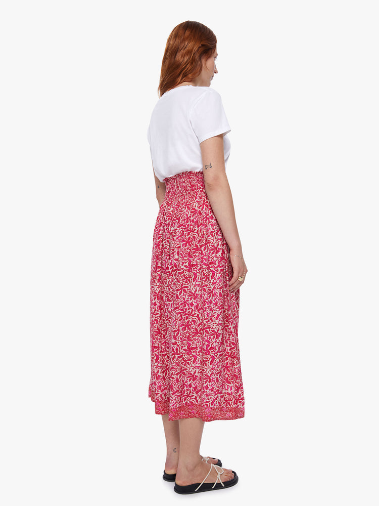 Back view of of a woman wearing a floral maxi skirt with a smocked waistband and loose flowy fit