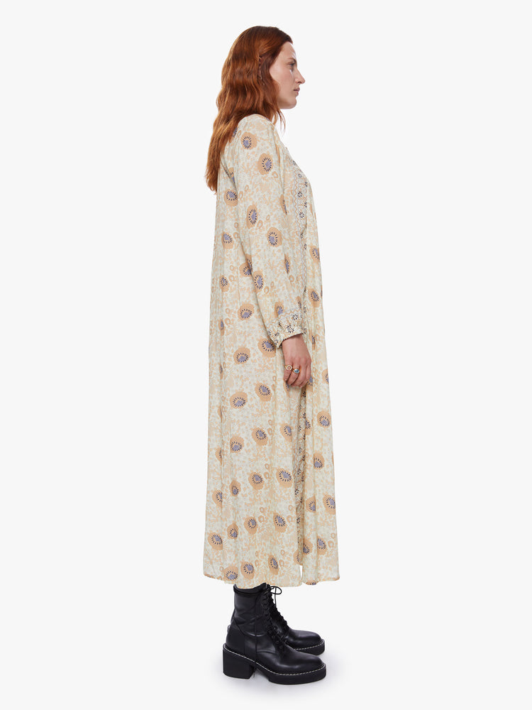 Side view of a woman wearing floral print maxi dress with voluminous sleeves and an A-line cut for loose breezy feel