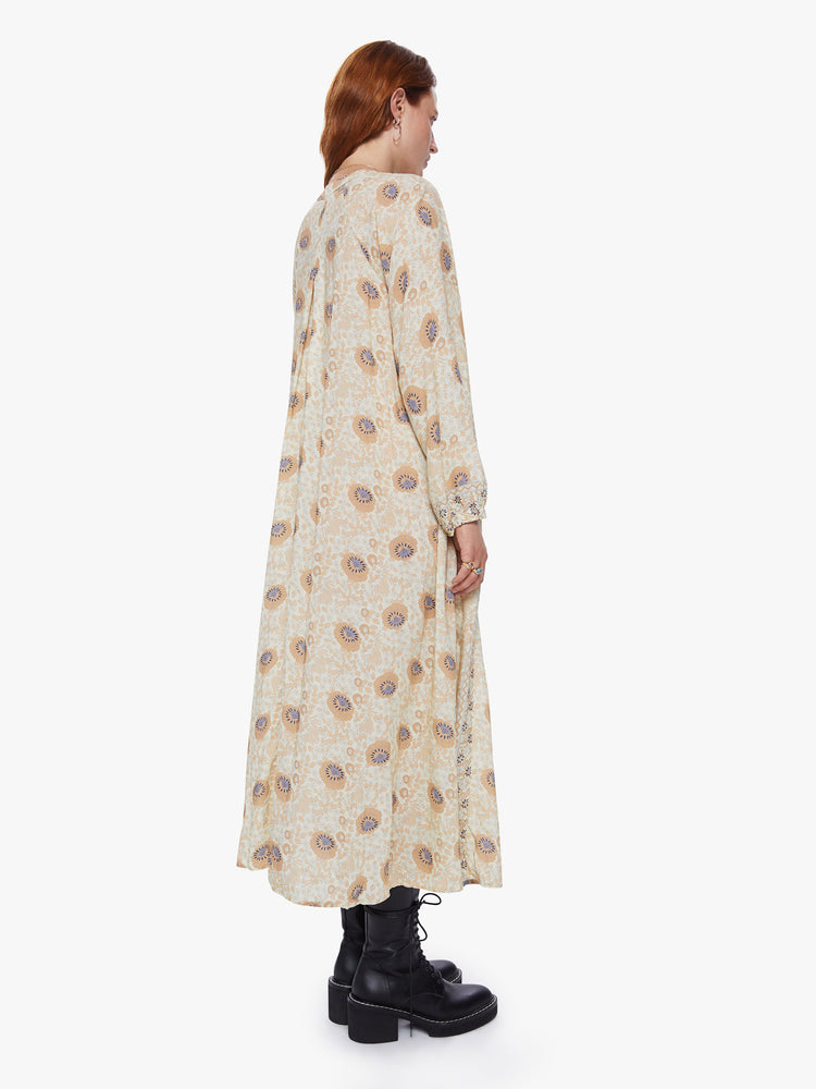 Back view of a woman wearing floral print maxi dress with voluminous sleeves and an A-line cut for loose breezy feel