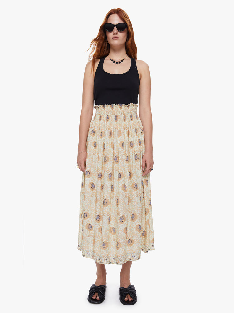 Front view of a woman wearing a beige floral maxi skirt with a smocked waistband and loose flowy fit