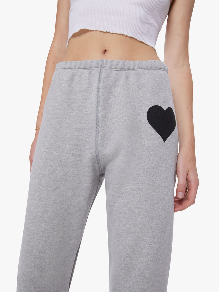 Detail view of a woman wearing heather grey sweatpants with a black heart on upper left leg