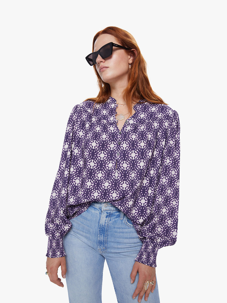 Front view of a womens v neck blouse featuring a white and purple print, billow sleeves, and a flowy fit.