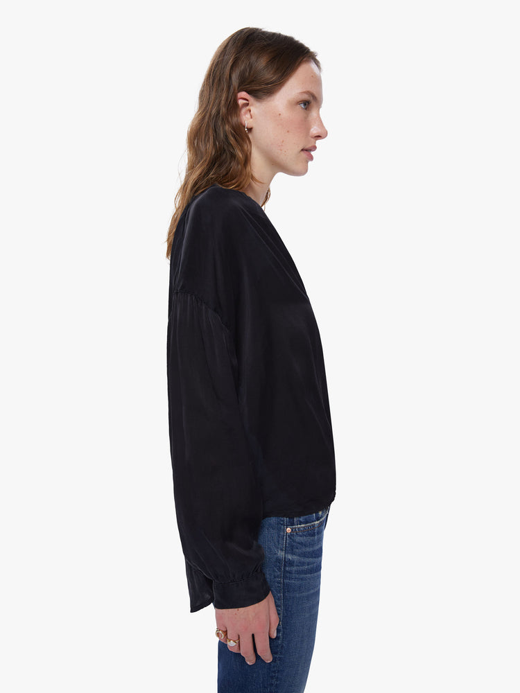 Side view of a womens black button down featuring a v neck and billow sleeves.