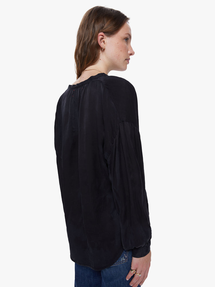 Back view of a womens black button down featuring a v neck and billow sleeves.