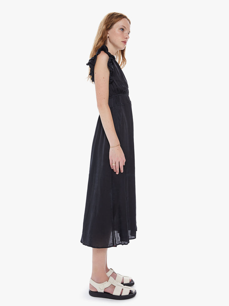 Side view of a womens black midi dress, featuring sleeveless ruffles, a deep v neck, and a smocked high waist.