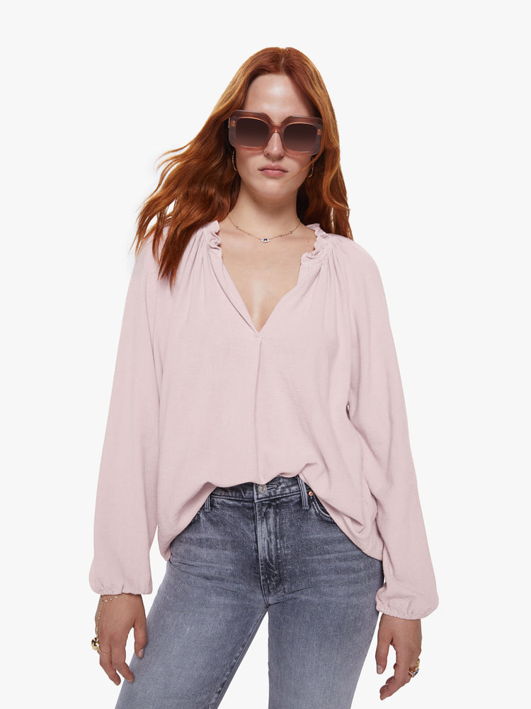 Front view of a womens pink v neck blouse featuring a ruffled collar, billow sleeves, and a flowy fit.