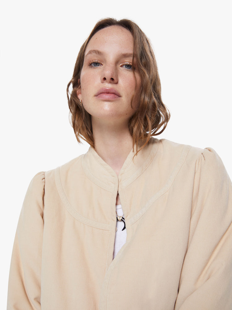 Front close up view of a womens beige jacket featuring a beige trim and a cropped boxy fit.