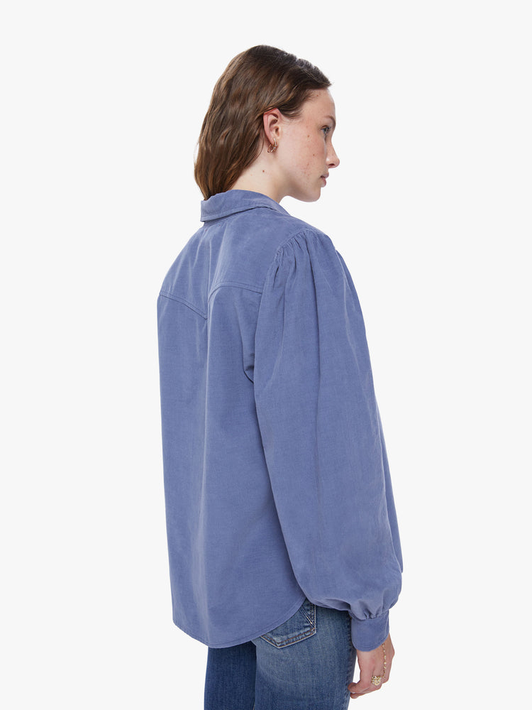 Back view of a womens blue button down shirt, featuring a chest pocket and long billow sleeves.