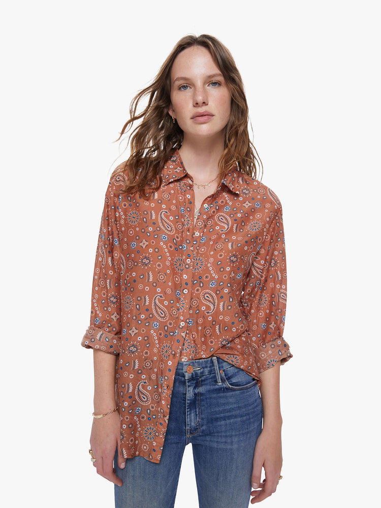 A front view of a woman wearing a burnt orange button up shirt with paisley print