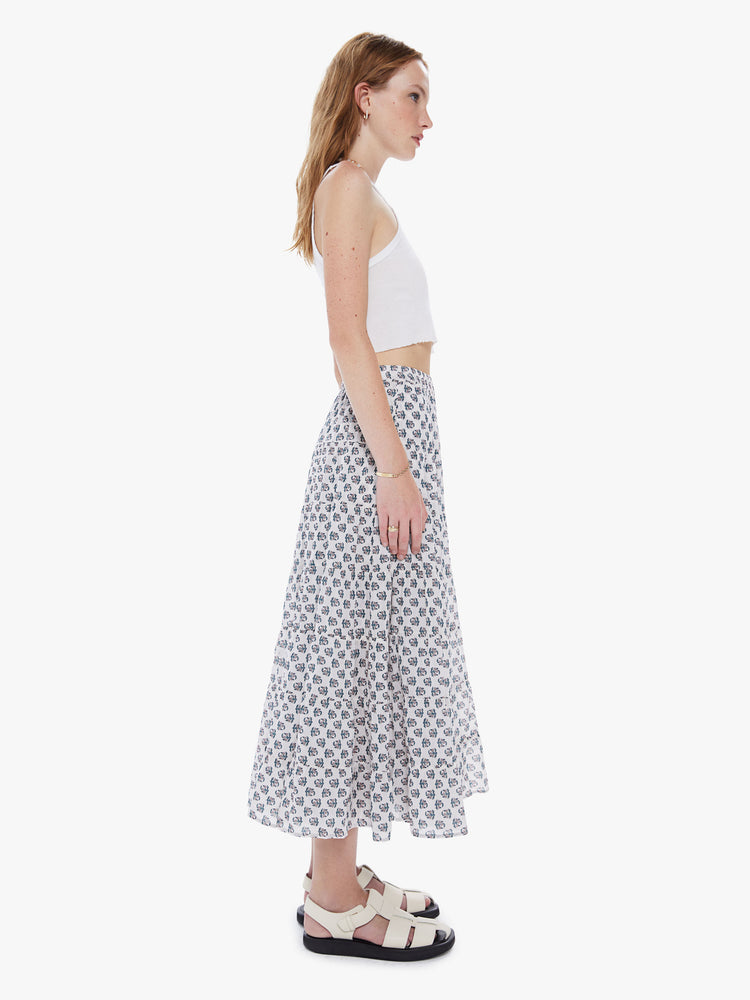 A side view of a woman wearing a white maxi skirt with a delicate floral print
