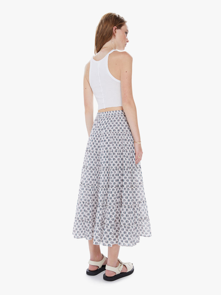 A back view of a woman wearing a white maxi skirt with a delicate floral print