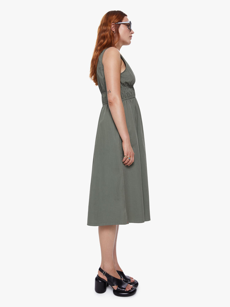 A side view of a woman wearing an olive green midi dress with a deep v neckline