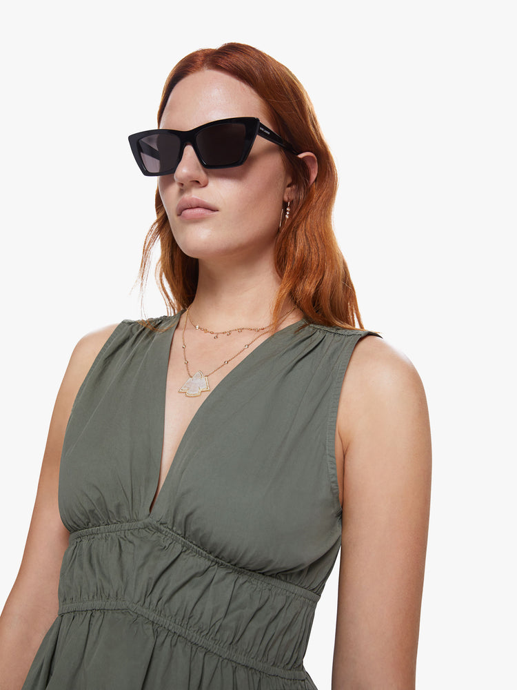 A detail view of a woman wearing an olive green midi dress with a deep v neckline