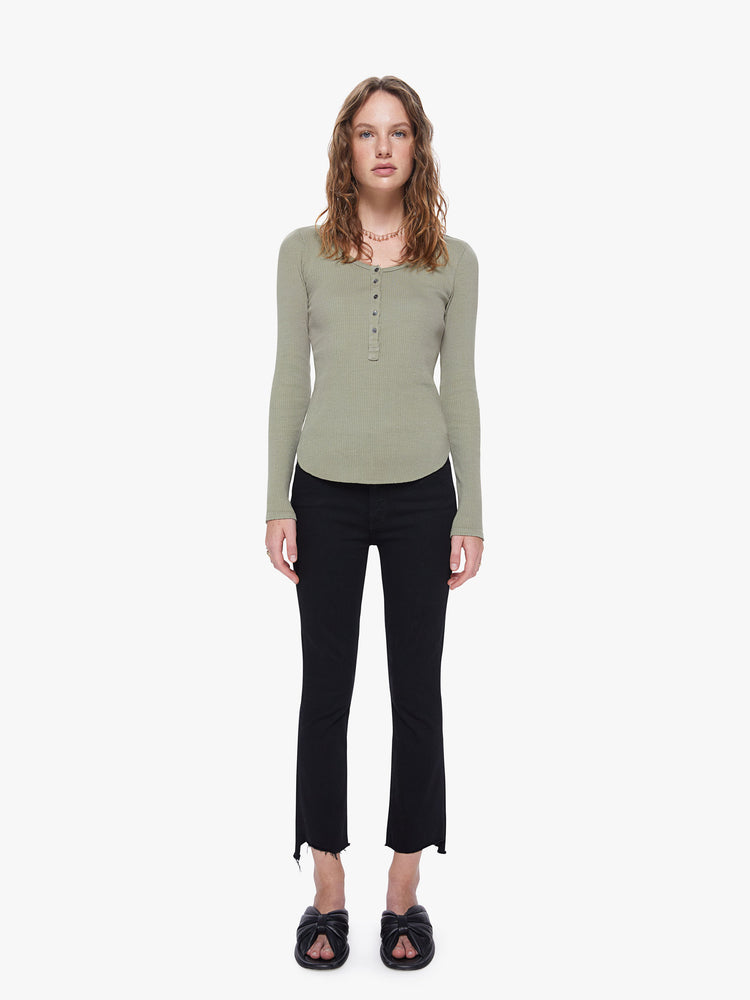 A full body view of a woman wearing a green, long sleeve henley top