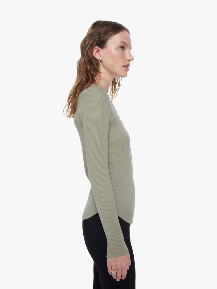 A side view of a woman wearing a green, long sleeve henley top