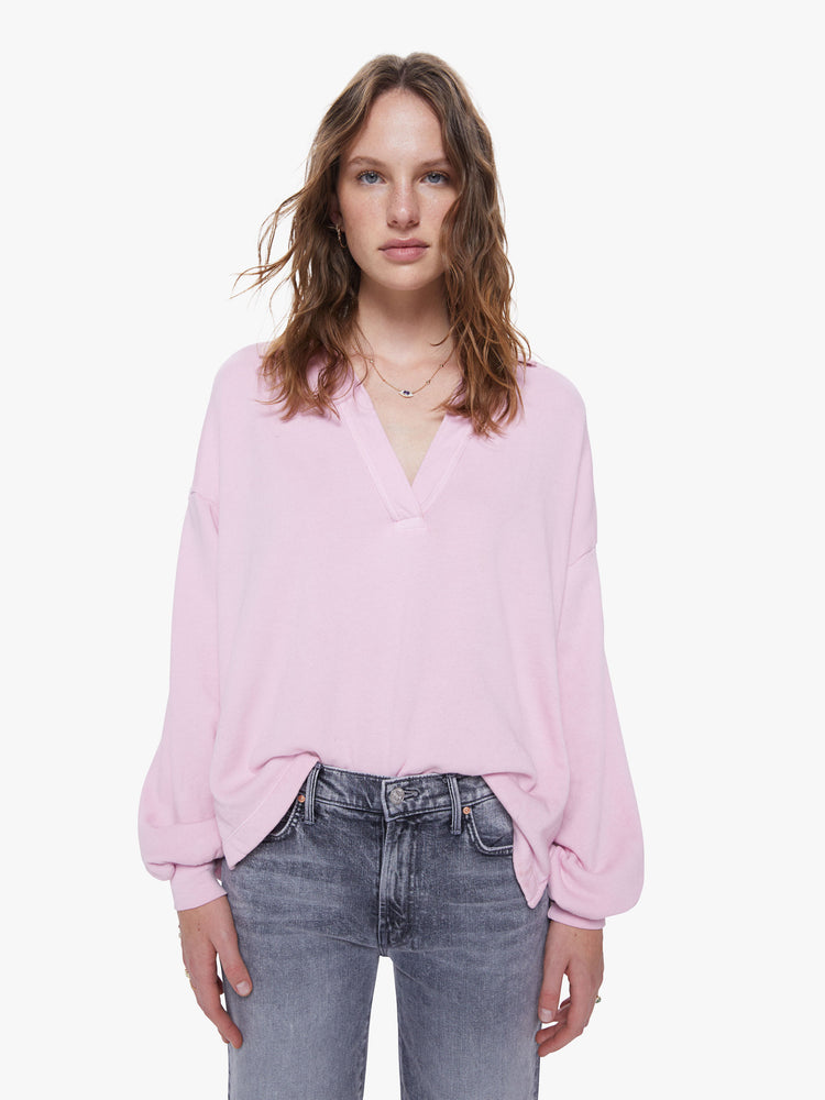 A front view of a woman wearing a light pink sweatshirt with a deep v, collared neckline