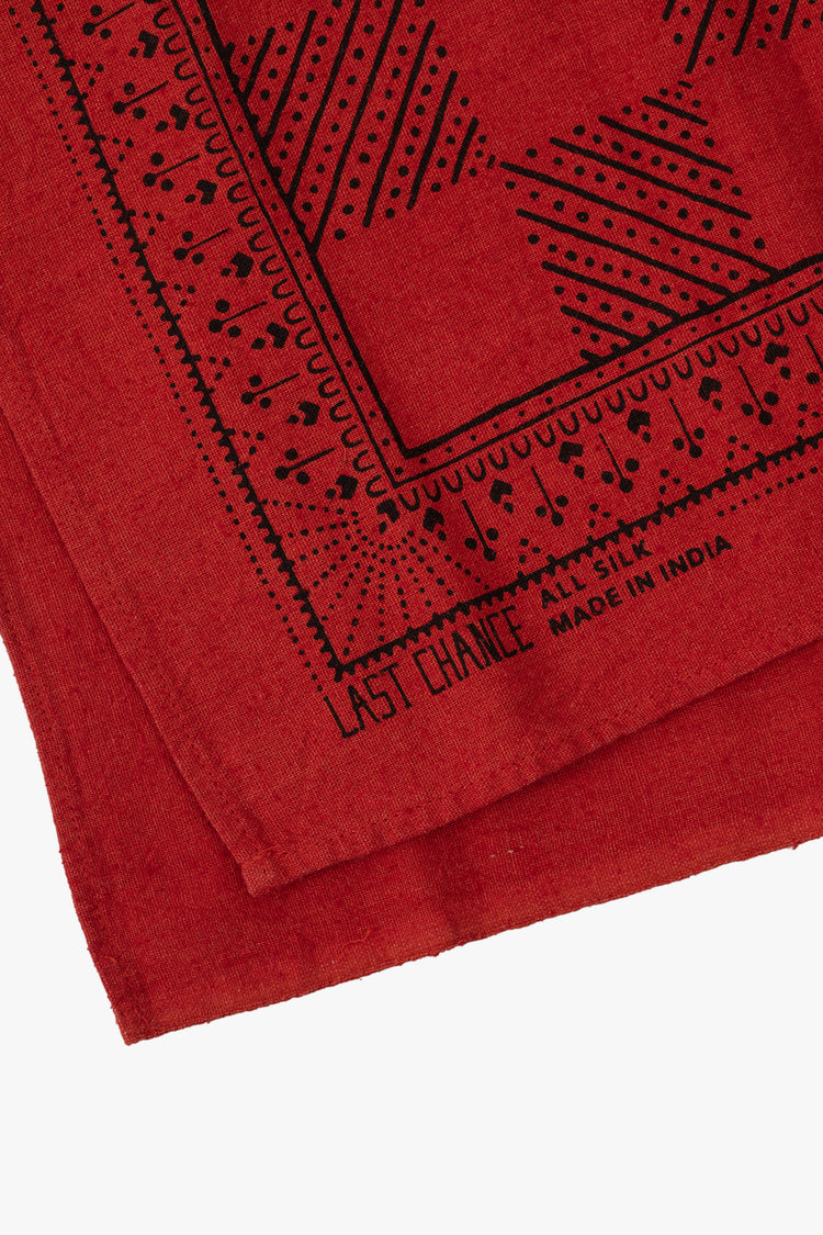 Top close up view of a folded red bandana featuring a black checkerboard print.