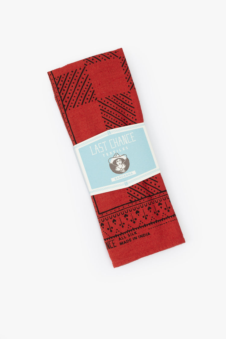 Top view of a folded red bandana featuring a black checkerboard print, in a light blue packaging.