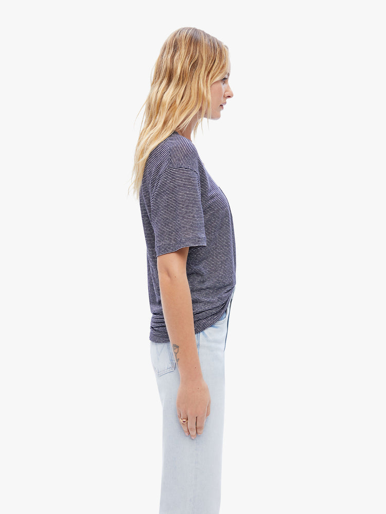 Side view a woman in a timeless La Paz tee that is soft and slightly oversized for a loose, comfortable fit cut from 100% linen, this classic crewneck tee features a dark navy stripe pattern