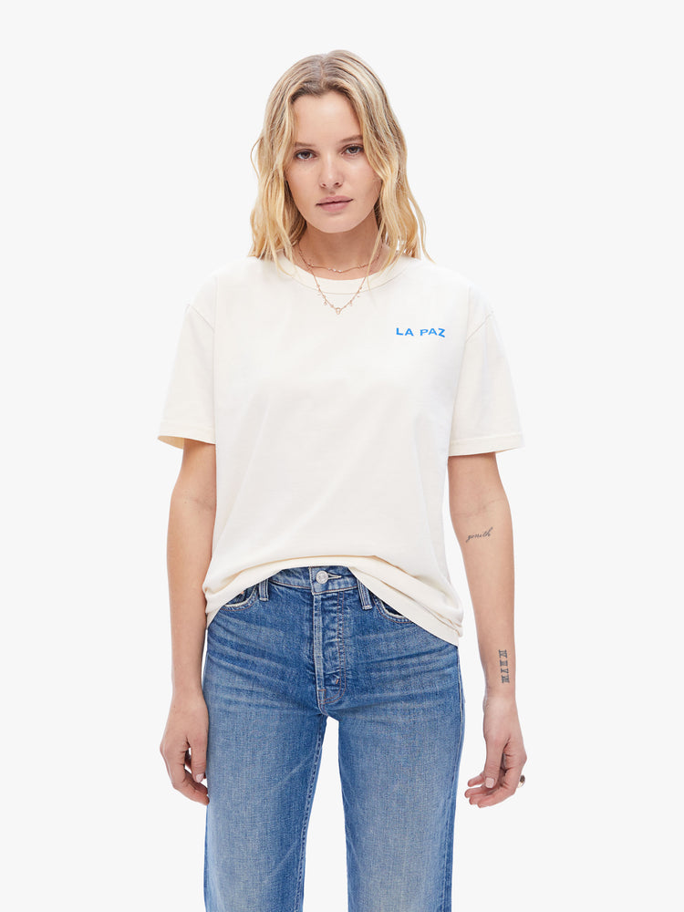 Front view of a woman in classic tee from La Paz, the white classic crewneck tee features the brands logo on the front and a blue circle on the back