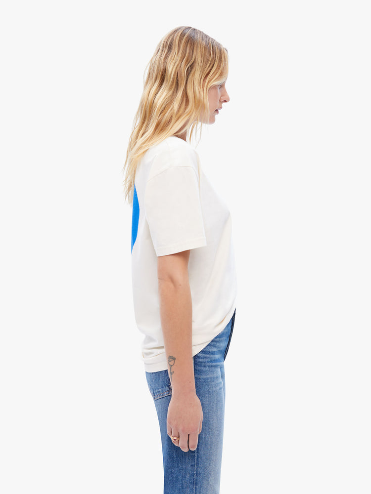 Side view of a woman in classic tee from La Paz, the white classic crewneck tee features the brands logo on the front and a blue circle on the back
